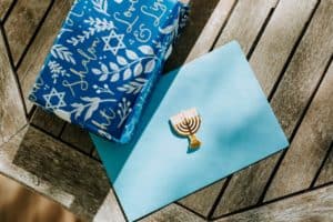 מתנה בעטיפה כחולה ומעטפה בצבע תכלת עם חנוכיה על גביה